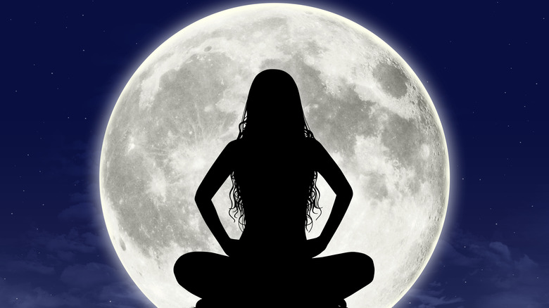 woman sitting in front of moon 