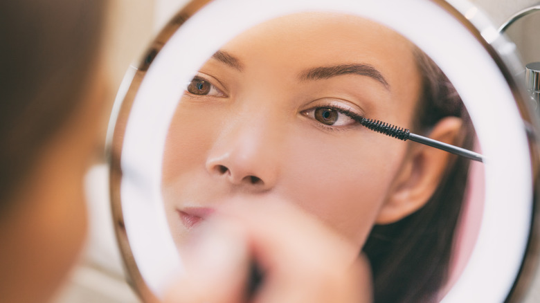 woman applying mascara on eyelashes