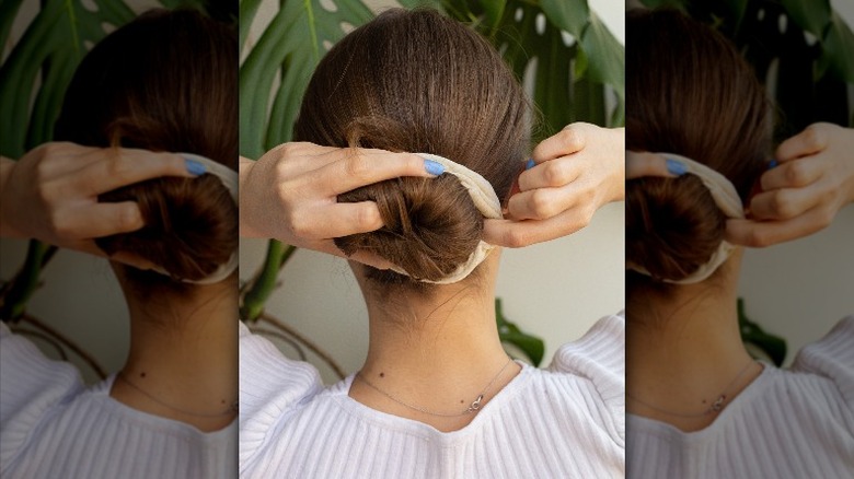 woman styling hair into bun 