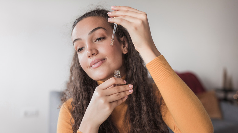 woman applying serum to face