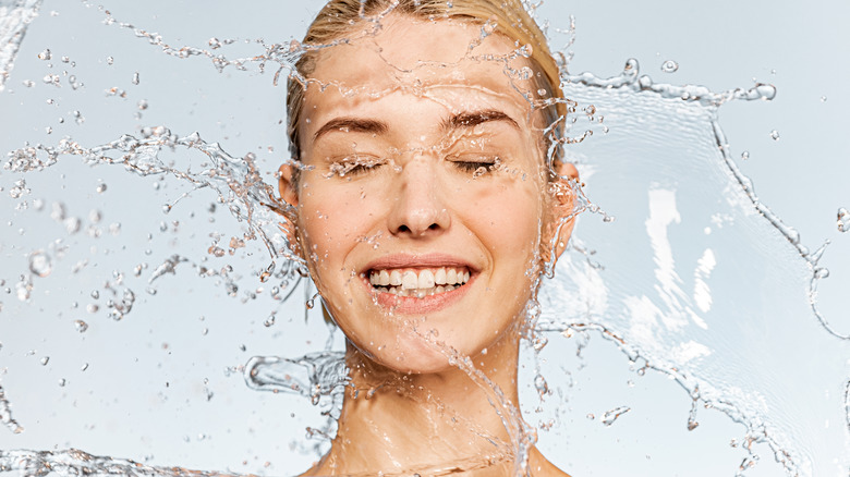 smiling woman splashing water on face