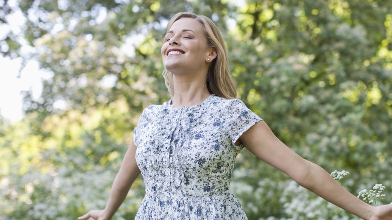 Woman holds her arms out to embrace the spring weather