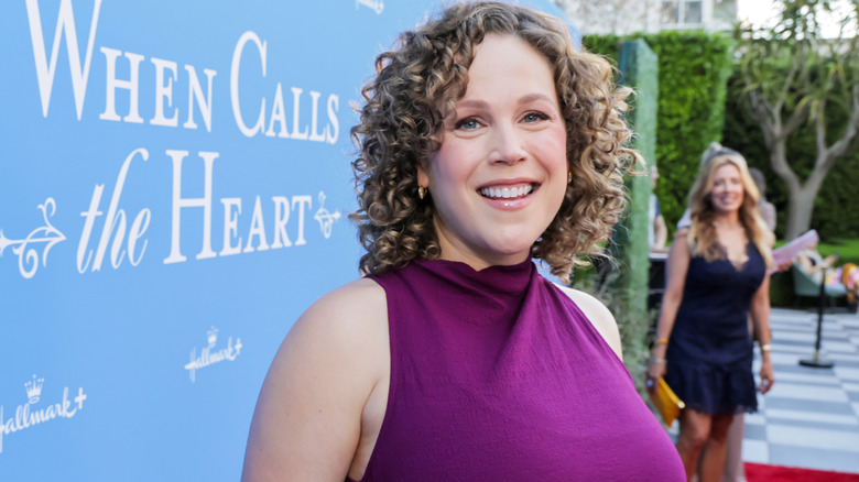 Actor Erin Krakow is pictured with curly hair on the red carpet while wearing a vibrant purple dress