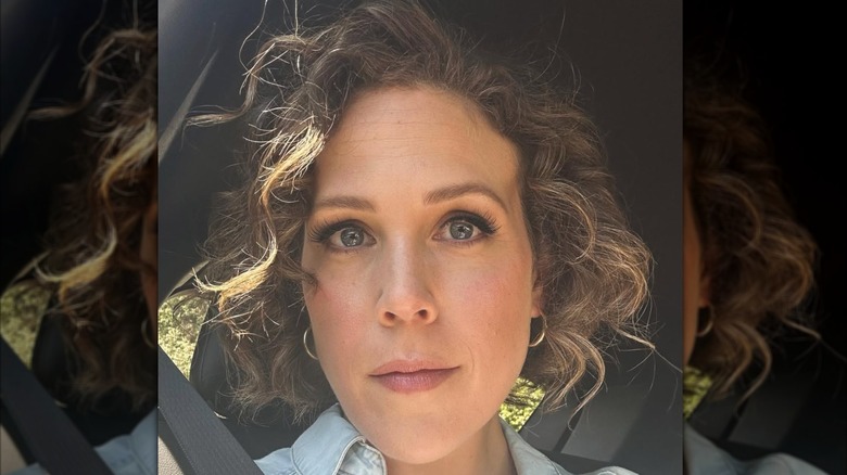 Erin Krakow is seen in a close-up selfie with short curly hair and soft glam makeup.