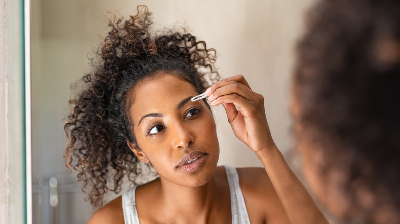 woman tweezing eyebrows