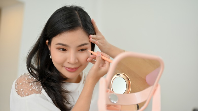 woman drawing eyeliner