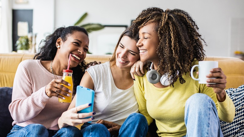 Three friends laughing on couch