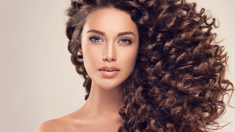 Woman poses with thick curly long hair