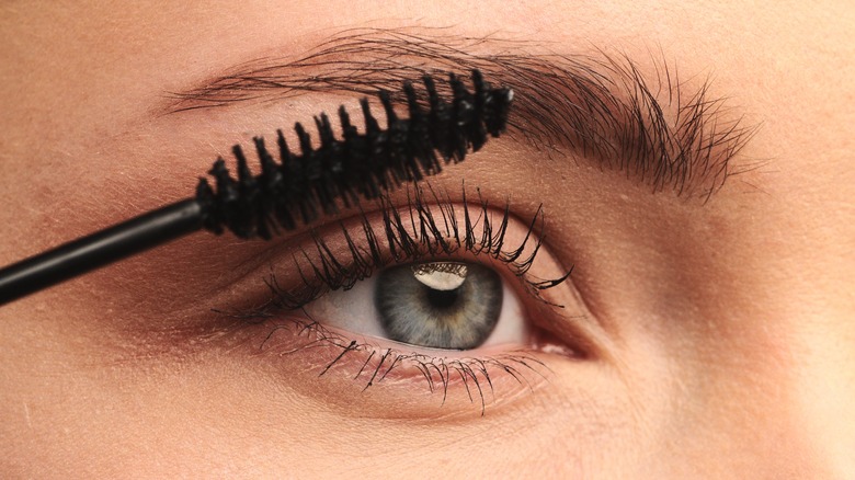 Person applying mascara with wand