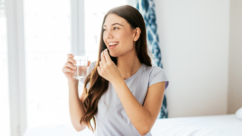 woman taking pill holding water