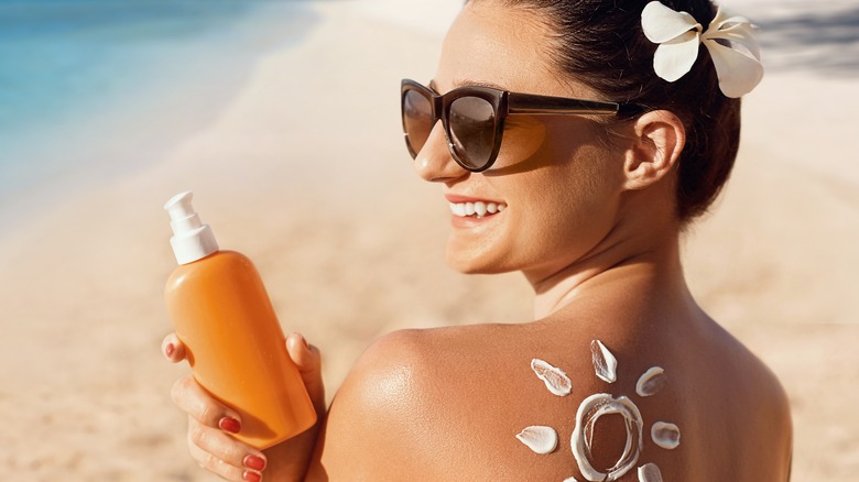 female tanning applying sunscreen