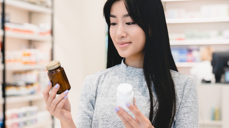 woman shopping for vitamins holds up 2 bottles to consider