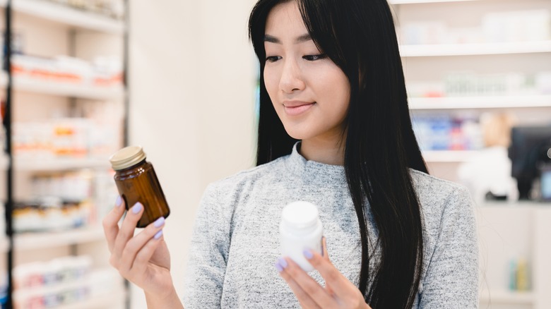 woman shopping for vitamins holds up 2 bottles to consider