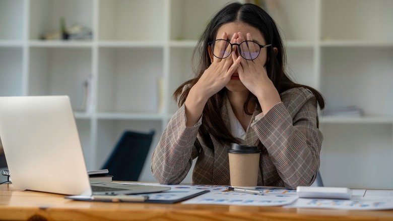 Stressed out businesswoman rubs eyes