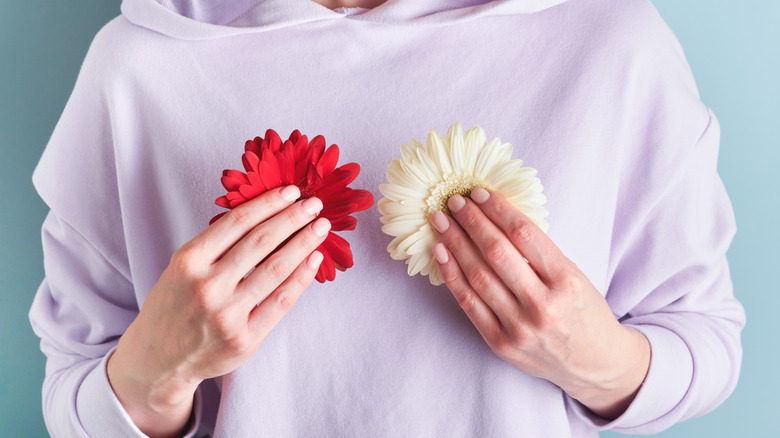 Woman holding two flowers in front of her breasts