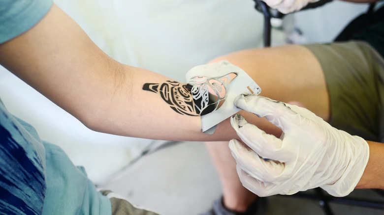 person peeling at a tattoo