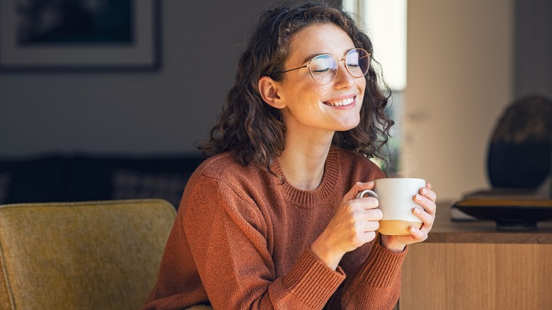 Woman joyously holds coffee cup