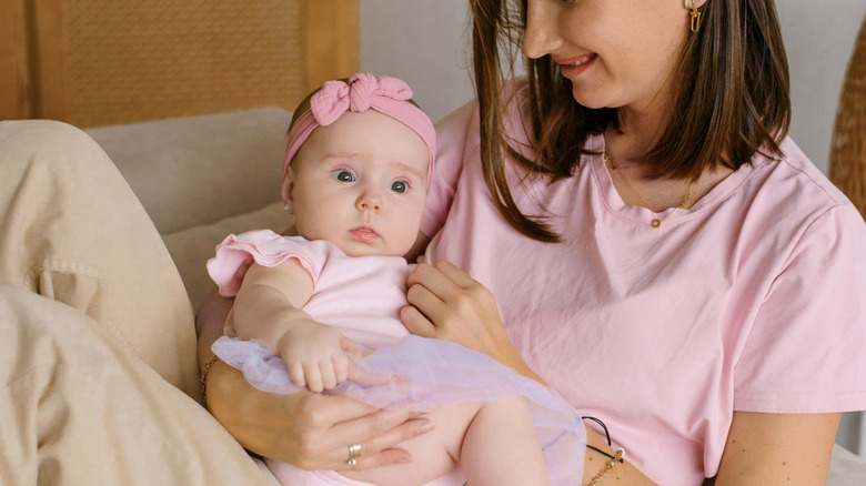 A mother holds a baby girl wearing a pink headband