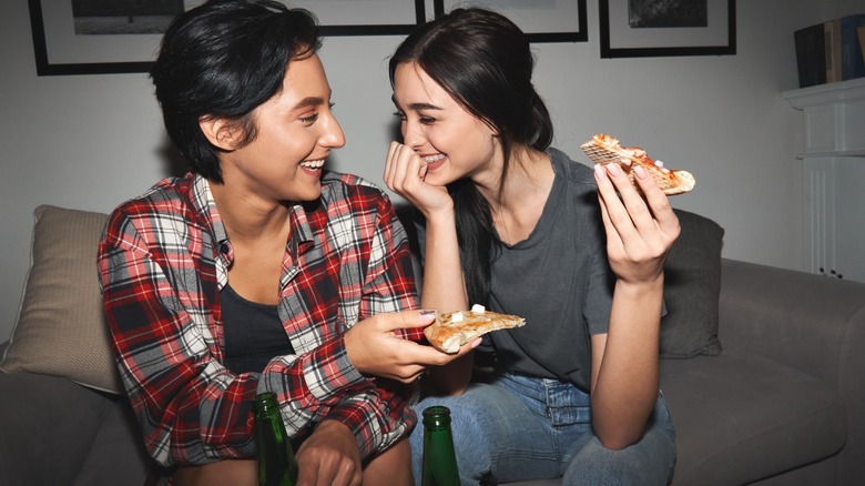 Two woman laughing with pizza