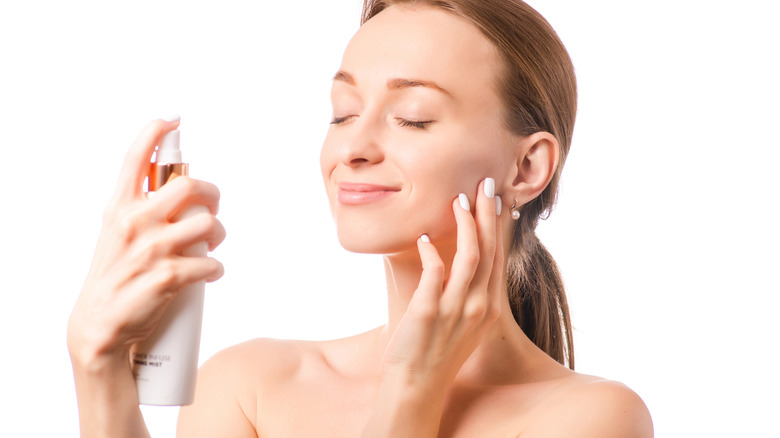 woman spraying face with spray