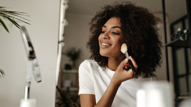 woman contouring face in mirror