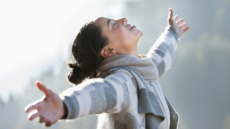 Young woman outside with arms spread