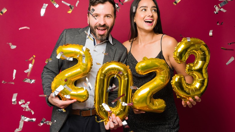 Happy people holding 2023 balloons