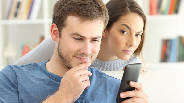 Man texting woman watching