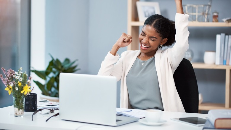 Ambitious woman celebrating at desk