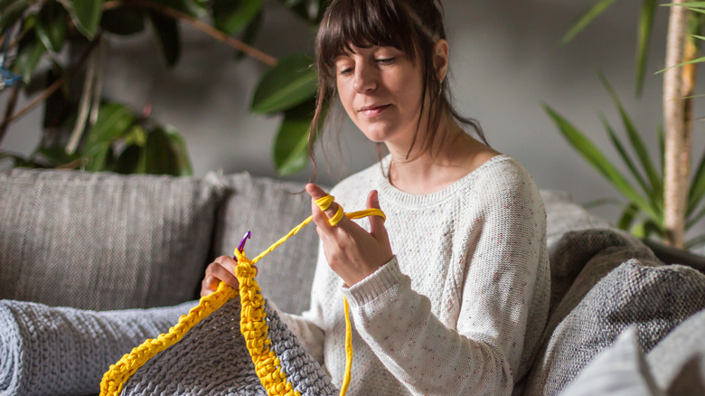 Woman crocheting on sofa