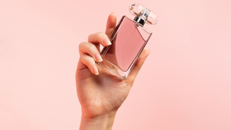 hand holding glass perfume bottle 