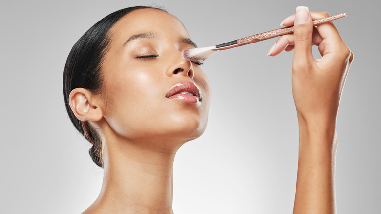 Woman applying highlighter to face 