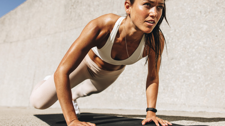 tanned female in white sportswear doing push-up