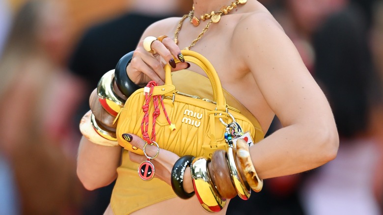 Gigi Hadid holding a yellow Miu Miu wearing stacks of bangles
