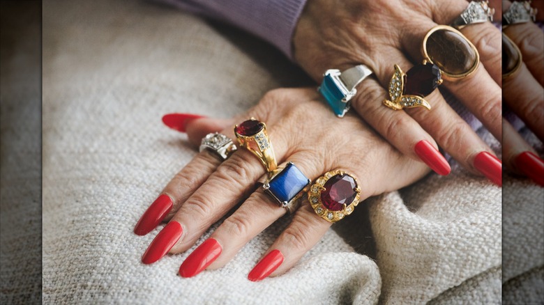 Long red nails wearing chunky rings
