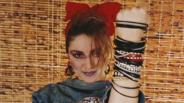 Madonna with an '80s-inspired style wearing a bracelet stack and a red headband