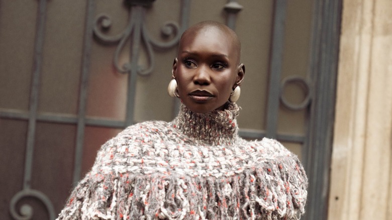 A woman with a shaved head wearing a knitted jumper and chunky silver earrings