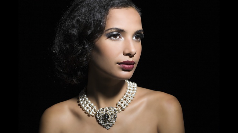 A brunette woman with a bob wearing a pearl and crystal choker