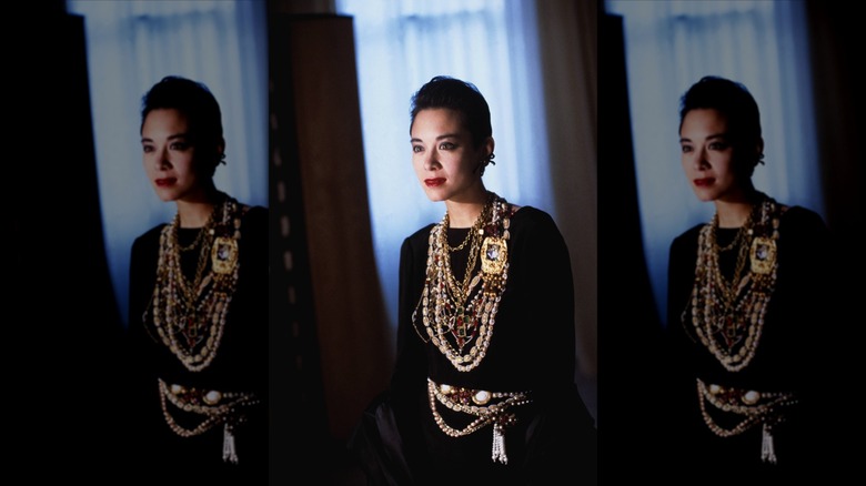 A brunette woman wearing a stack of gold chain necklaces
