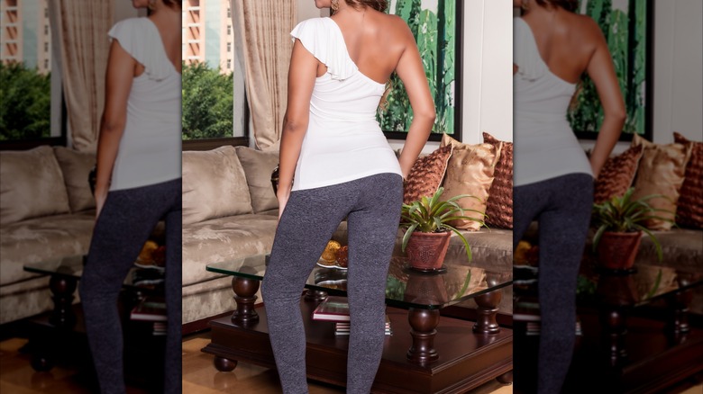Woman wearing a white fitted top and gray leggings