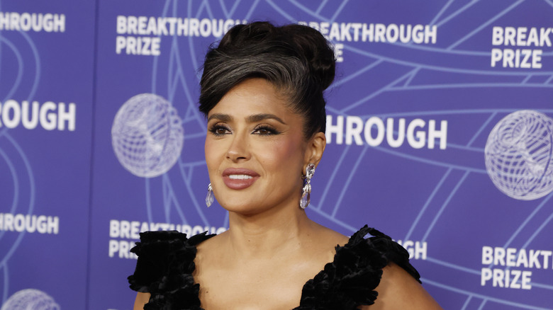 Salma Hayek poses at an event with her hair worn in an updo