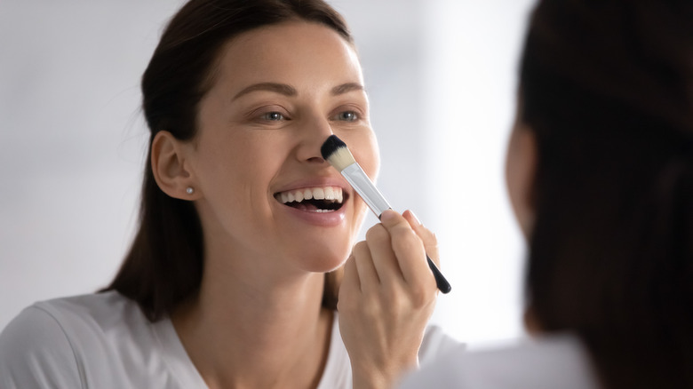 Woman applying makeup to her nose