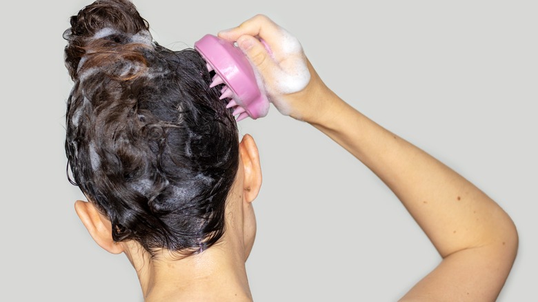 woman using a pink scalp massager