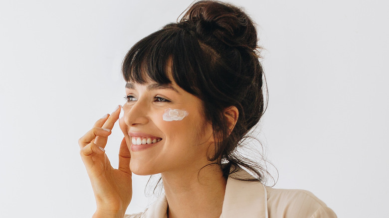 A happy woman applying face cream 