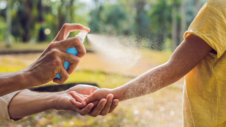 person applying spray sunscreen