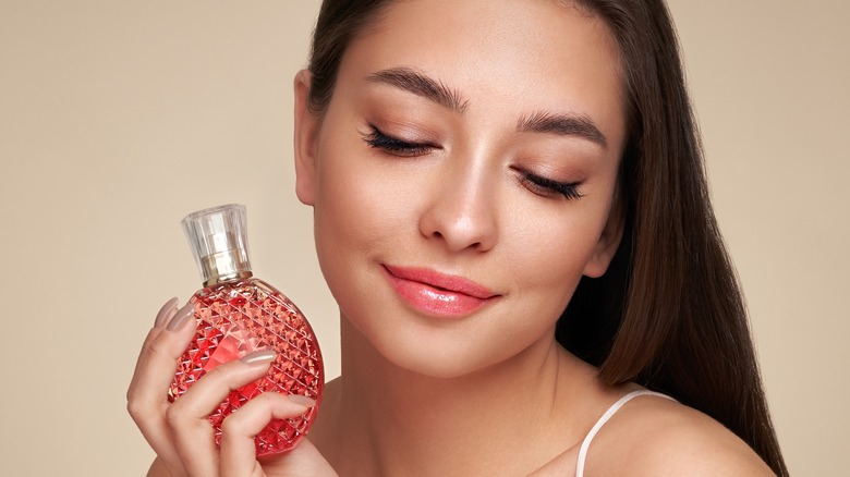 A woman holding a perfume bottle