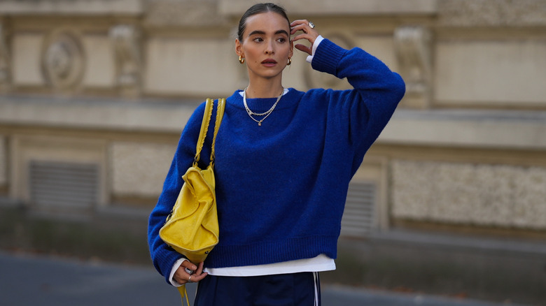 A woman wearing a blue sweater and track pants