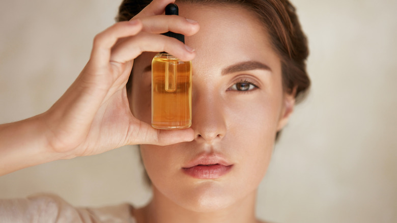 woman holding up bottle of serum to her eye