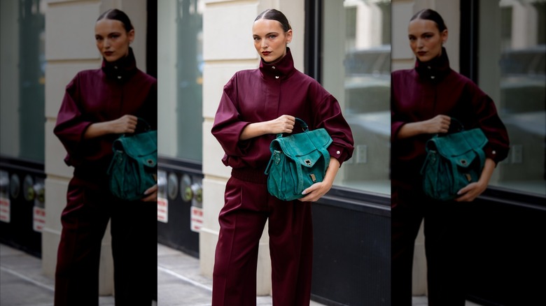 Woman in a burgundy outfit holding a green bag