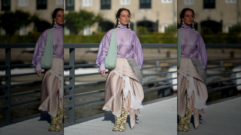 A woman wearing neon yellow snakeskin boots and a pale pink wrap skirt.